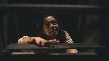 Tess (Georgina Campbell) crawls up a set of dark wooden stars, crying, in Barbarian