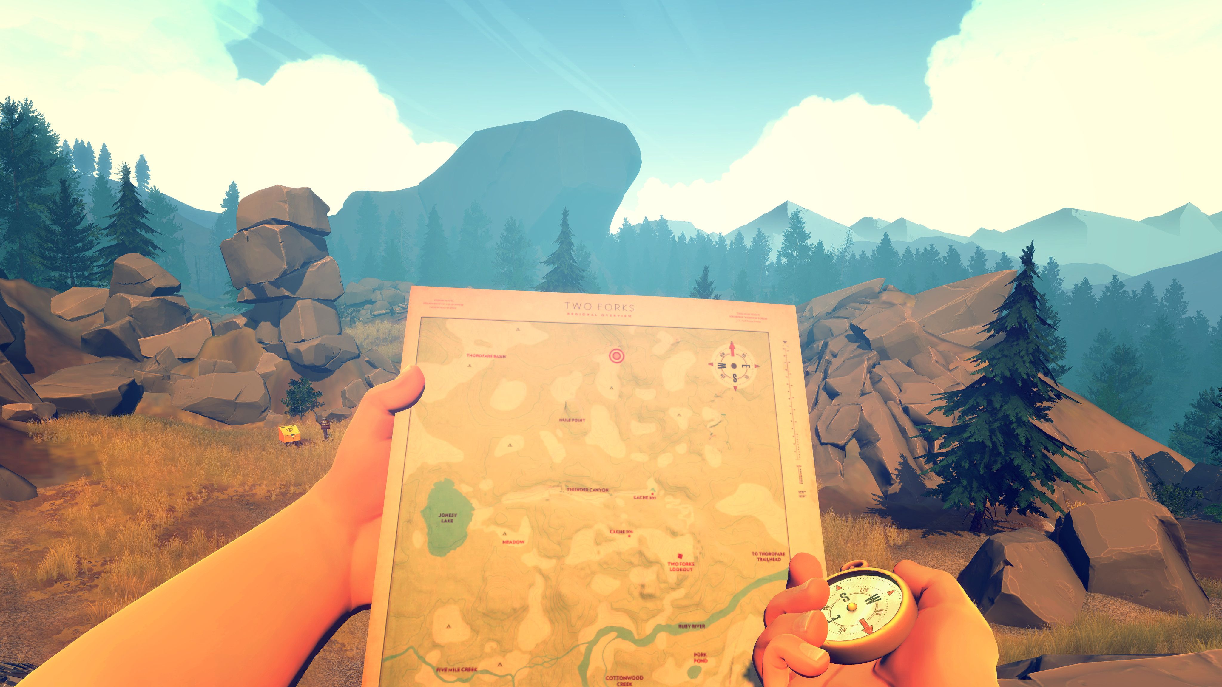 Hands hold a map and compass up in front of a rocky landscape in Firewatch
