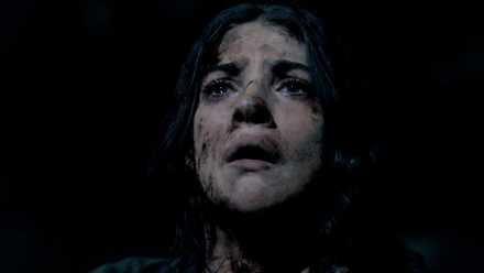 A young woman in the Until Dawn movie production gazes up, caked in dirt and filth, with a horrified expression on her face.