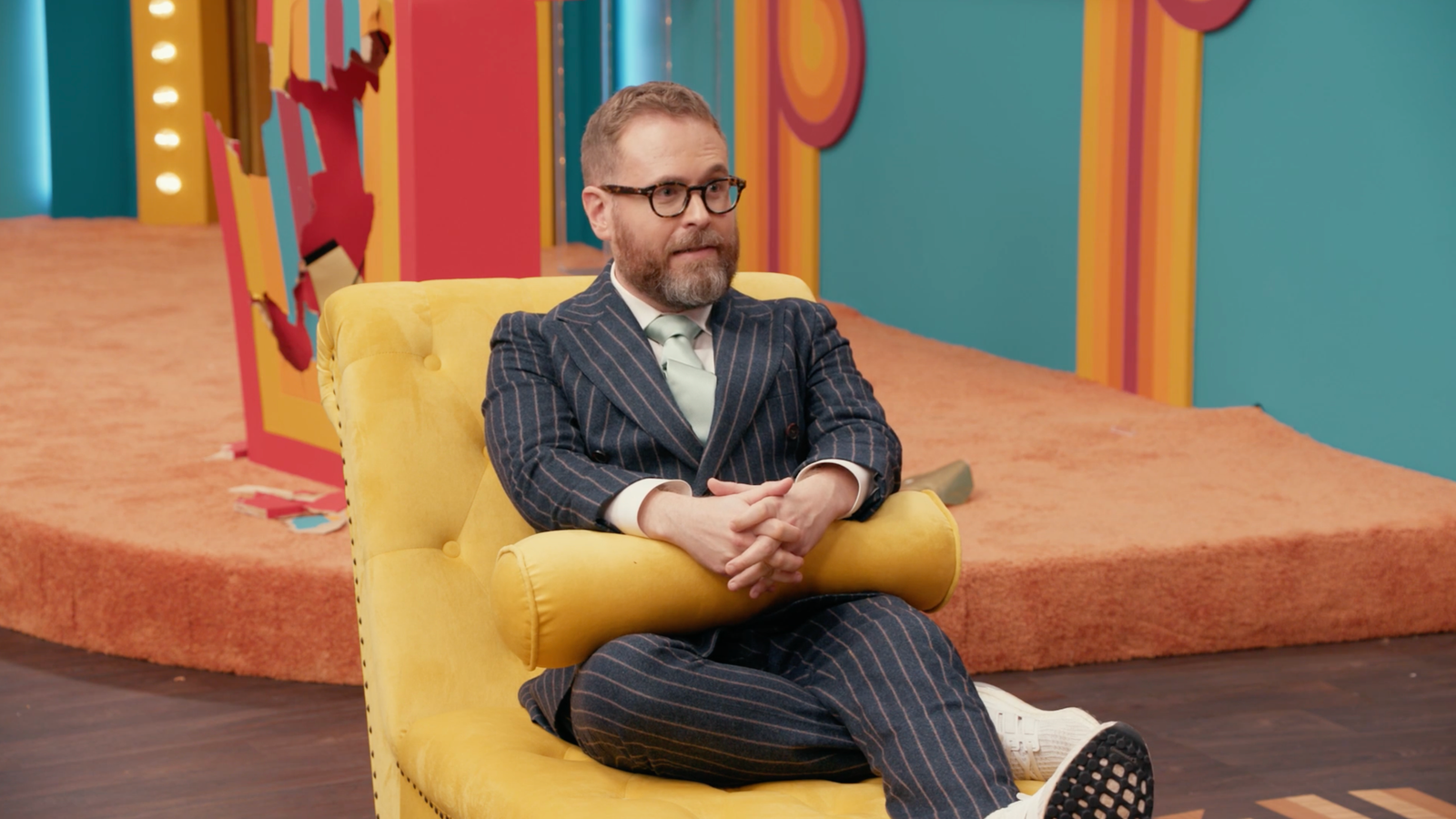 Sam Reich sitting on a therapist’s couch on the set of Game Changer.