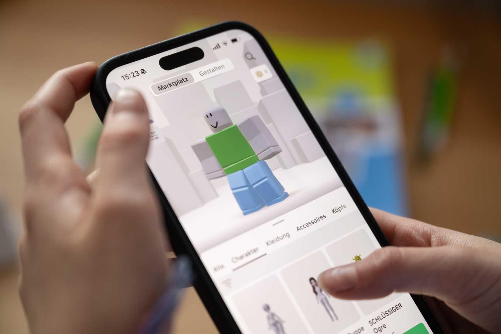 Hands holding a phone that shows a Roblox character