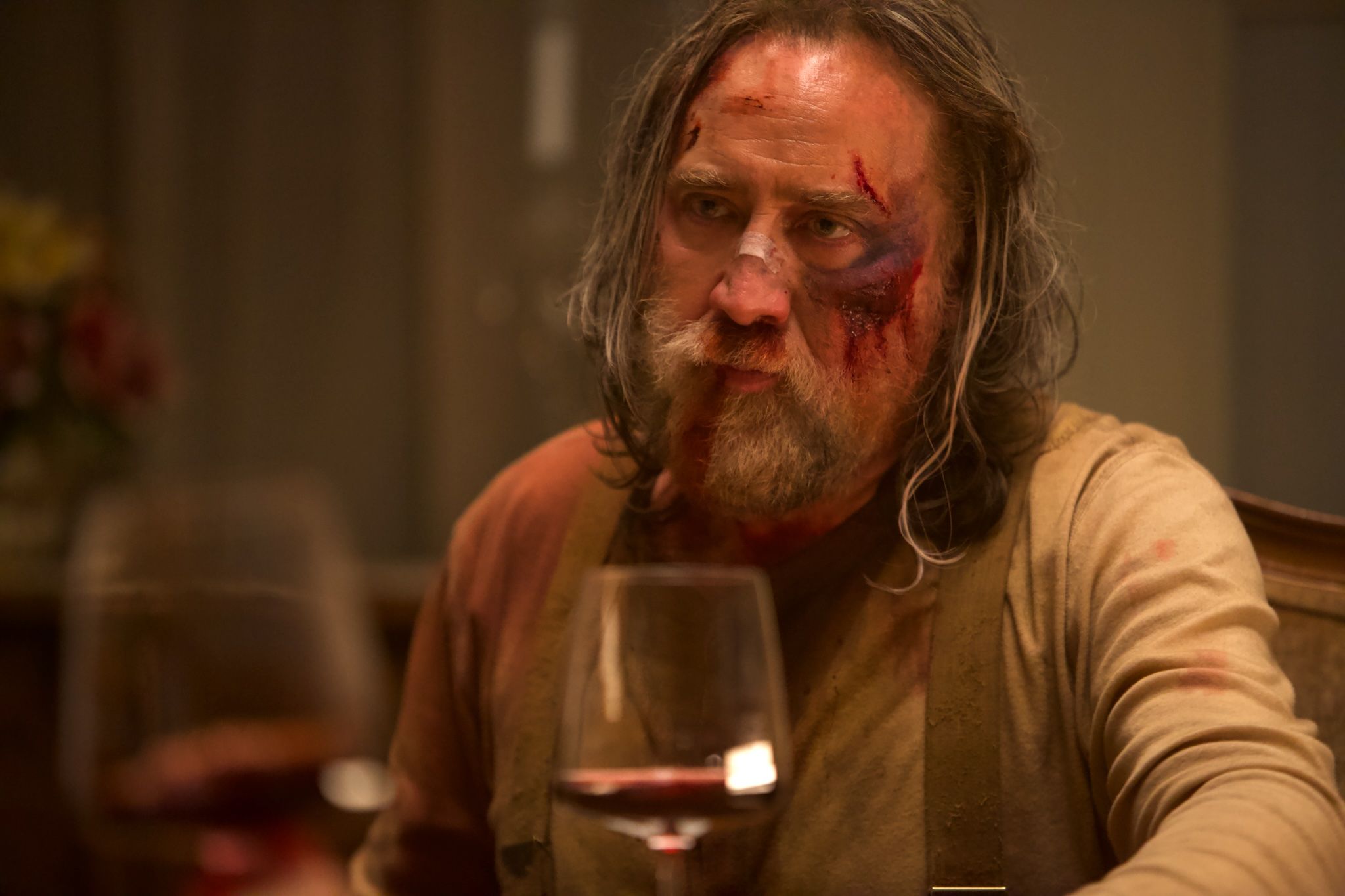 Nic Cage bleeding from his face in front of a wine glass in Pig