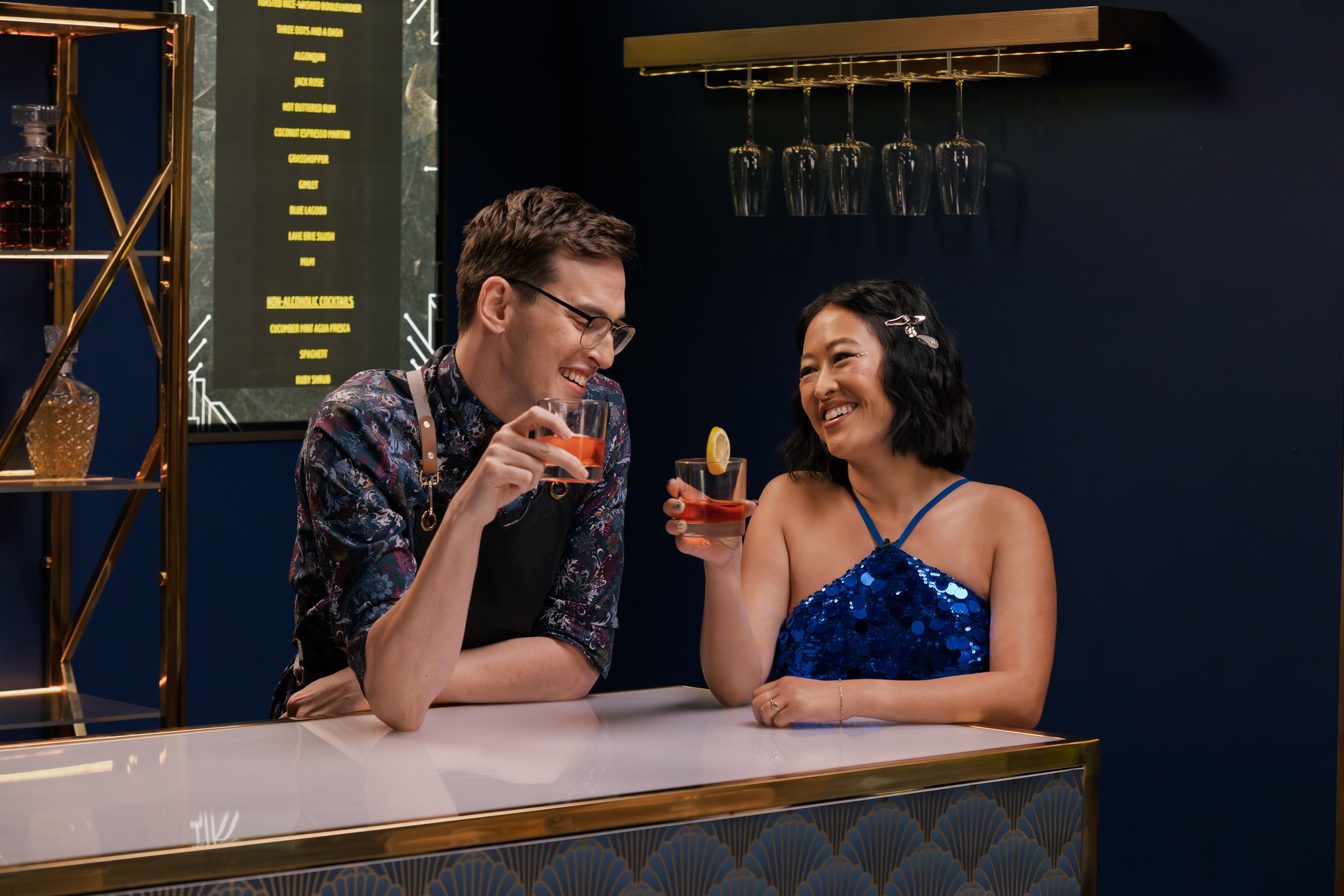 Grant O’Brien and Lily Du clinking glasses in the trailer for season 5 of Dropout’s Dirty Laundry.