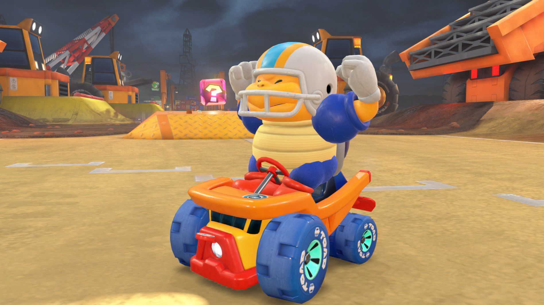 A Chargin’ Chuck poses and flexes while riding a dump truck toy kart in Mario Kart World.