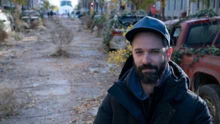 a man, Neil Druckmann, standing in the middle of an empty road on the set of HBO’s The Last of Us The Last of Us Season 1 - Episode 2 The Last of Us season 1, episode 2.