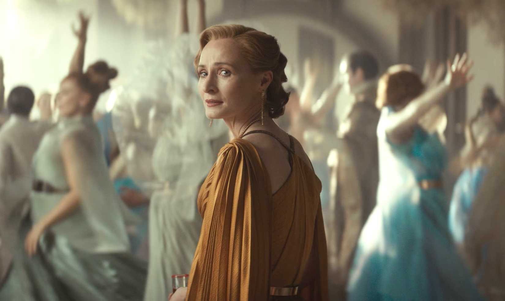 Mon Mothma from Andor season 2 looking over her shoulder at a wedding while wearing a golden dress