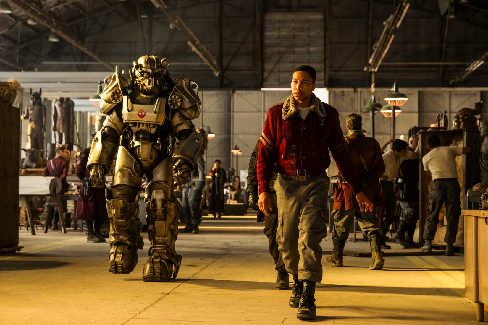 Aaron Motel as Maximus strides alongside a suit of Brotherhood of Steel Power Armor. Image from Prime Video's Fallout season 2.