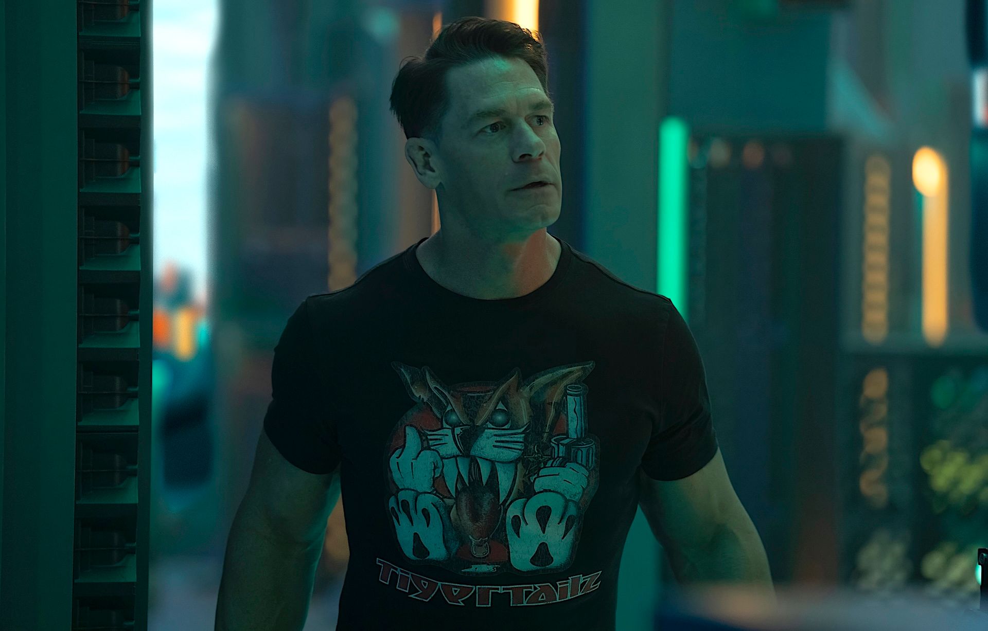 John Cena as Chris, aka Peacemaker, stands in a green-lit high-tech space in season 2, episode 1 of Peacemaker