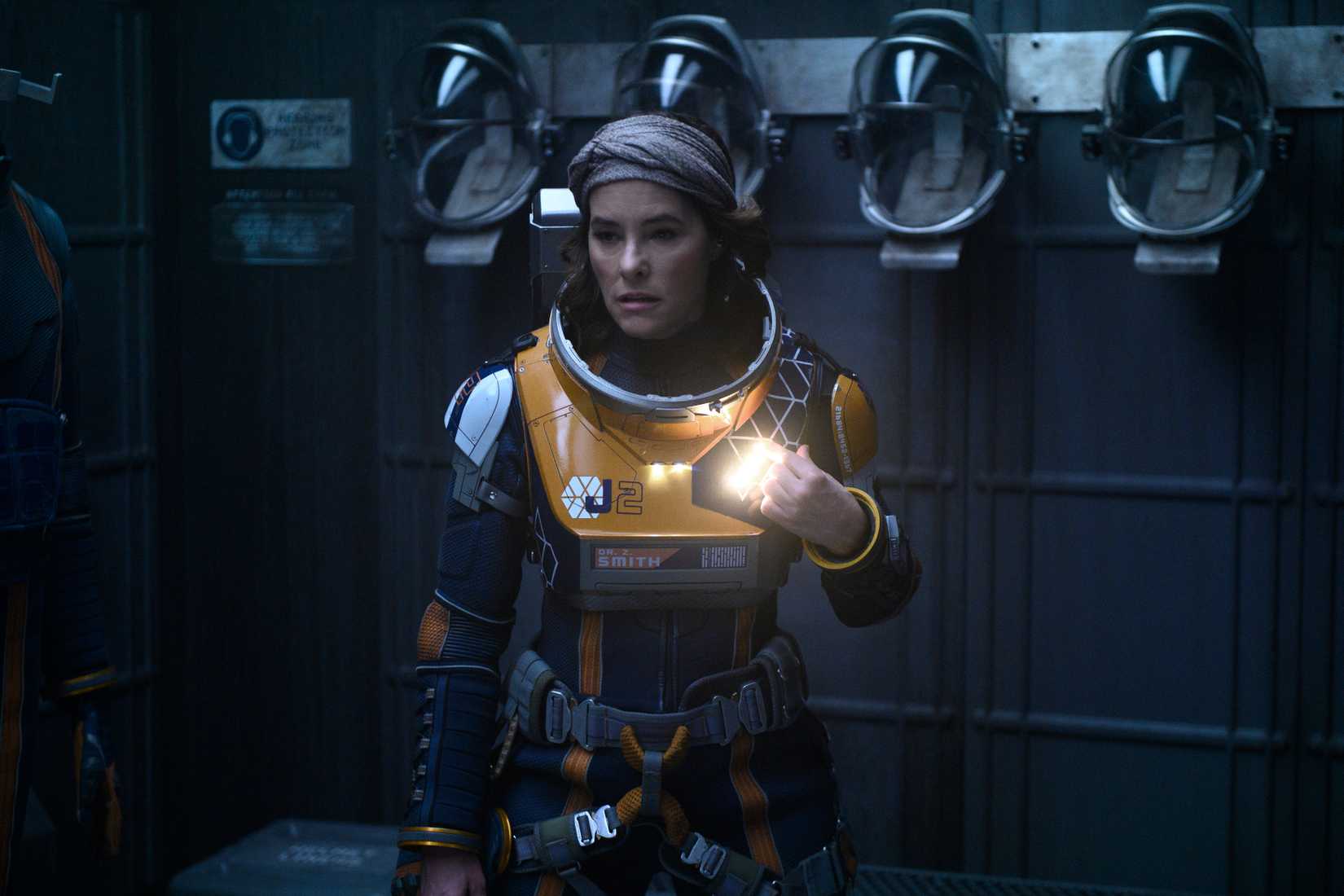 Parker Posey en un traje espacial sin que el casco se ve asustado en la temporada 2 de Lost In Space