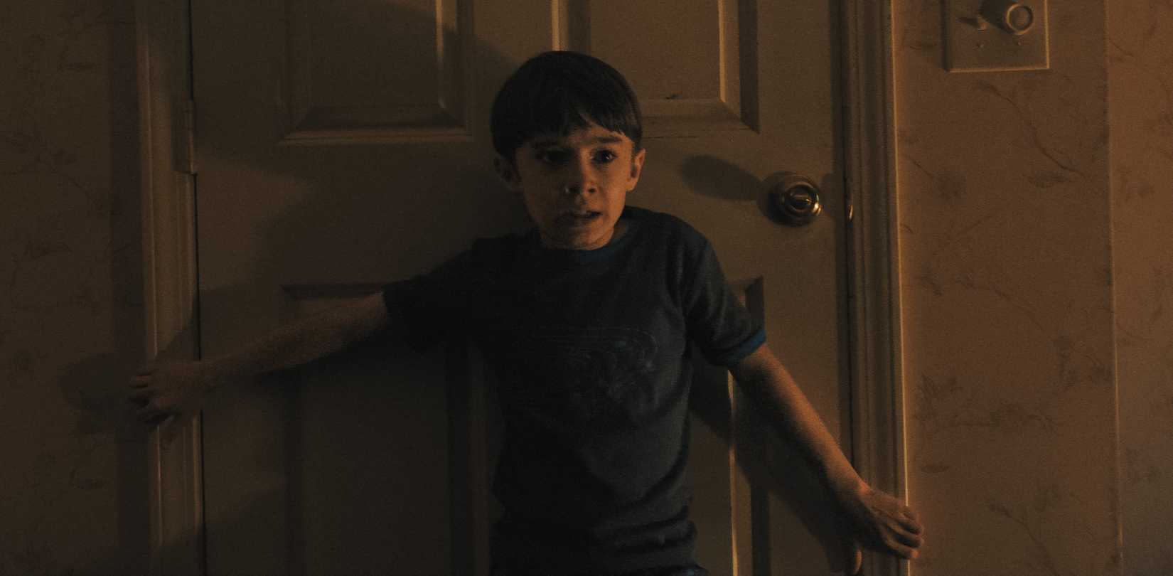 एक युवा घबराया हुआ लड़का अपनी पीठ के साथ एक बंद दरवाजे पर दबाया जाता है और उसकी बाहों को हथियारों में ब्लॉक करने के लिए बाहर निकाला जाता है