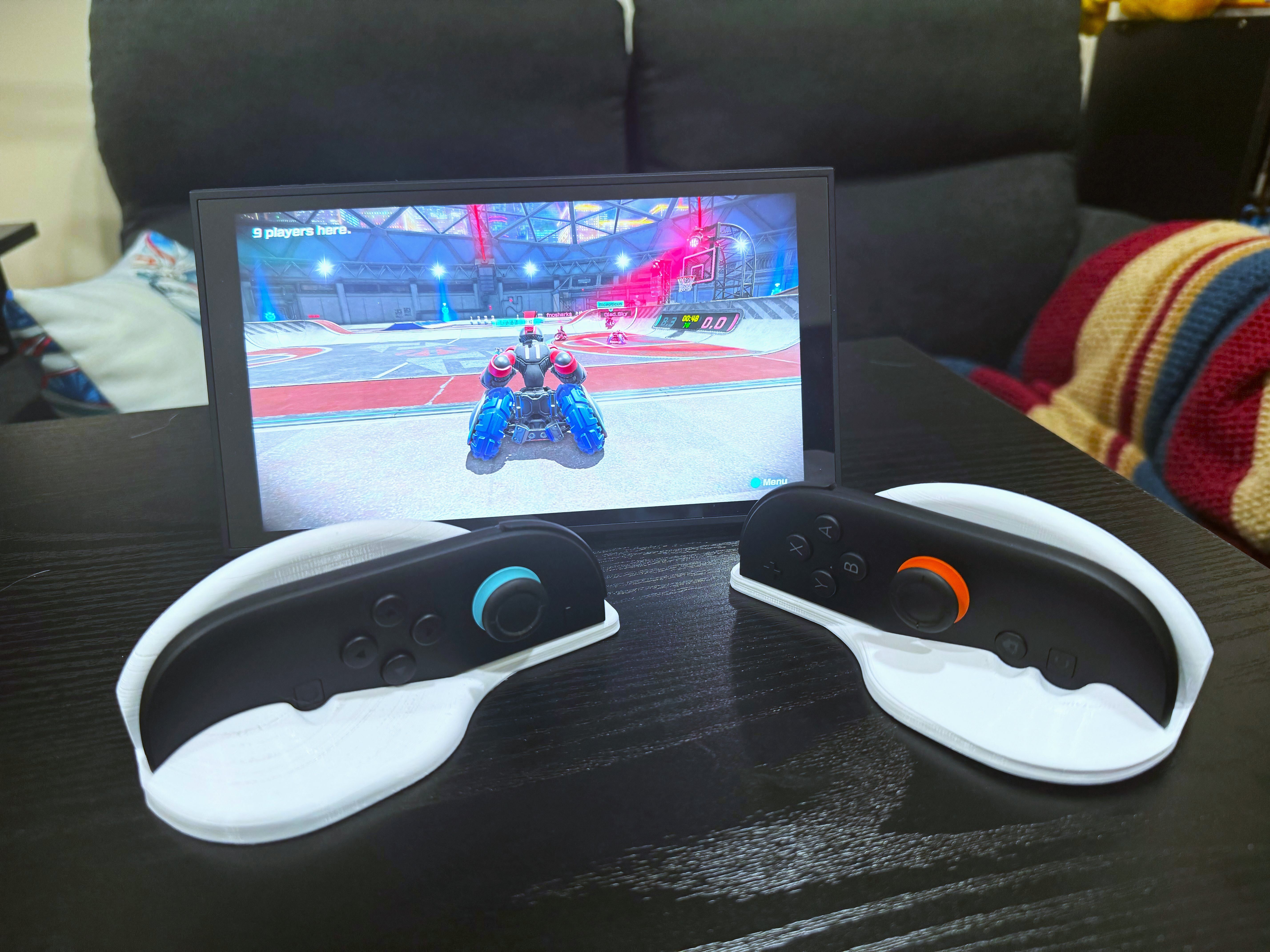 A Switch 2 sits on a table with Joy-Con controllers in a 3D printed mouse adapter.