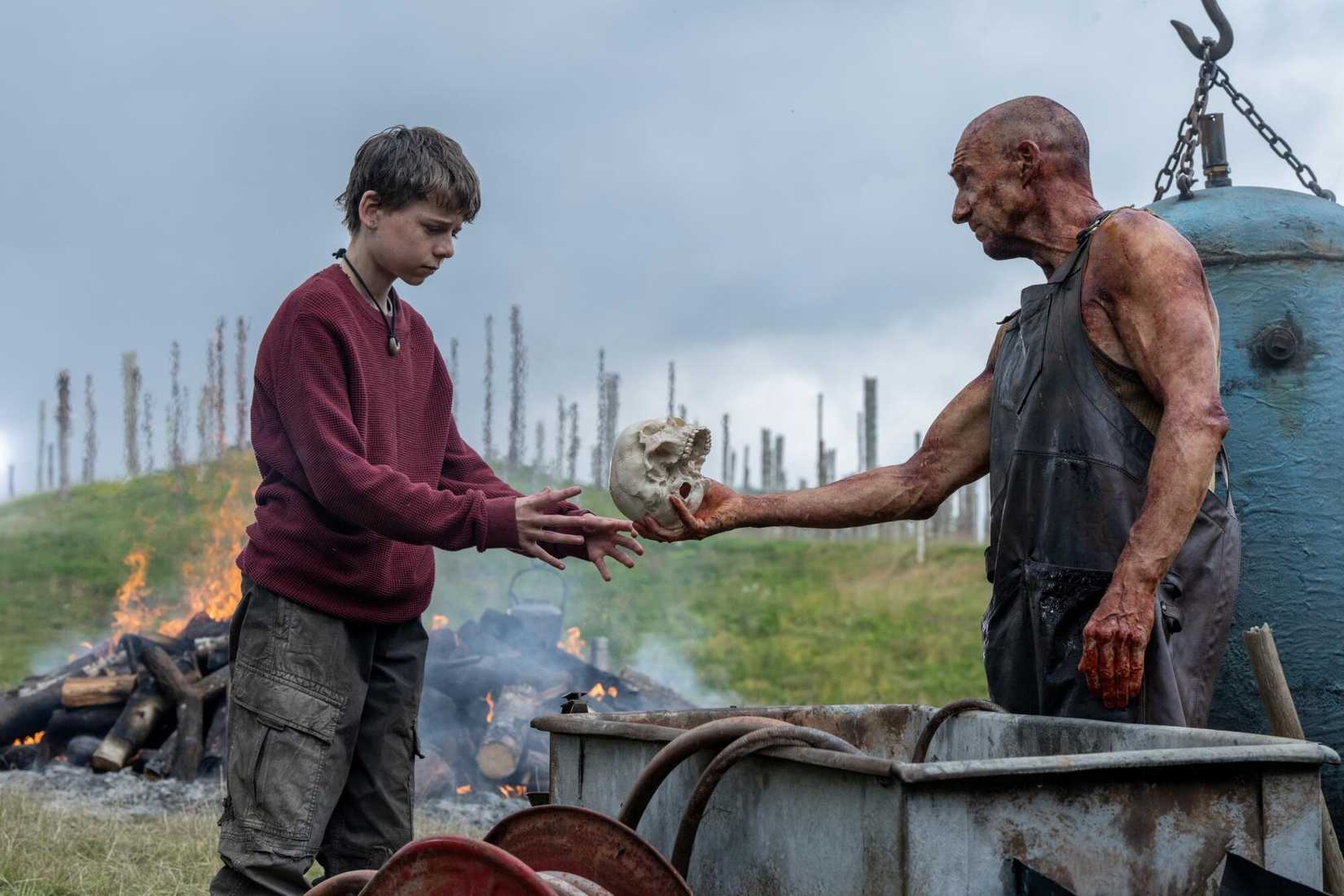 Twelve-year-old Spike examines a skull presented by a mysterious stranger played by Ralph Fiennes in a scene from 28 Years Later