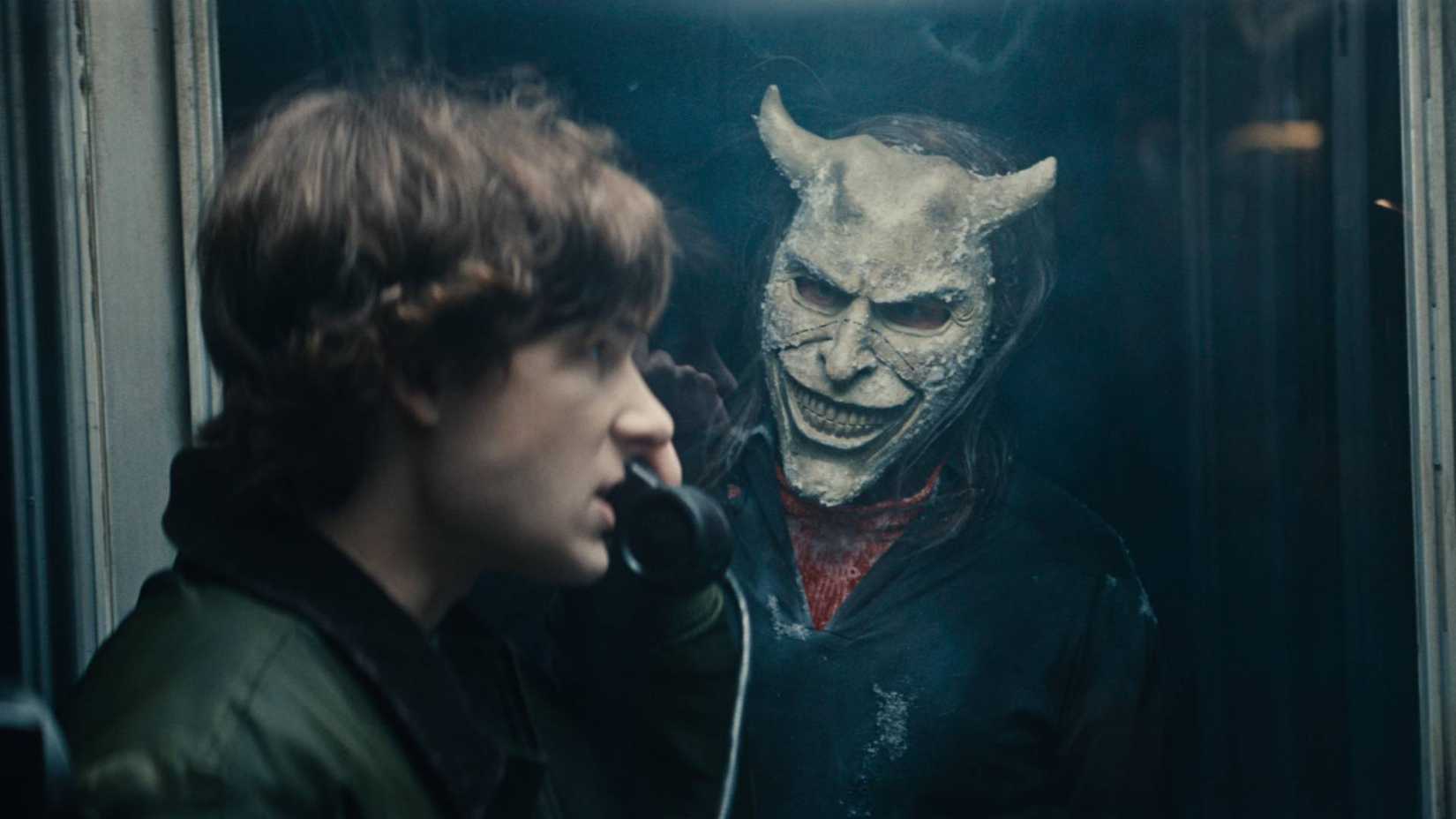 The Grabber looks at Finn in a phone booth in Black Phone 2