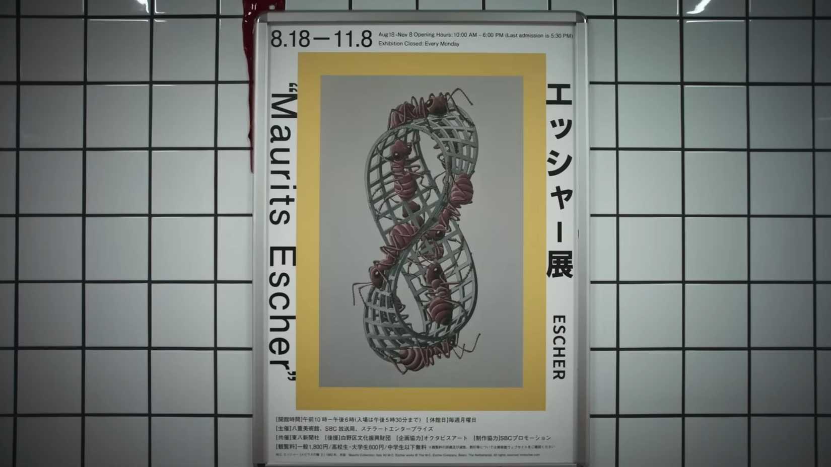 A screenshot from the exit 8 trailer showing one of the posters present in the corridor where there are some text and a Moebius strip with ants walking on it