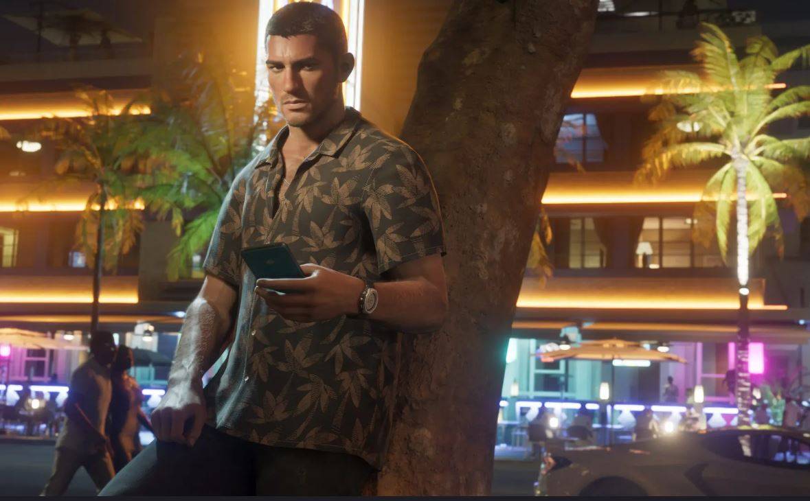GTA 6, जेसन में दो नायक में से एक, एक फोन रखता है क्योंकि वह एक पेड़ के खिलाफ झुक जाता है। वह पृष्ठभूमि में शहर की नाइटलाइफ़ हलचल के रूप में पत्तियों के साथ एक पैटर्न वाली शर्ट पहने हुए है। 