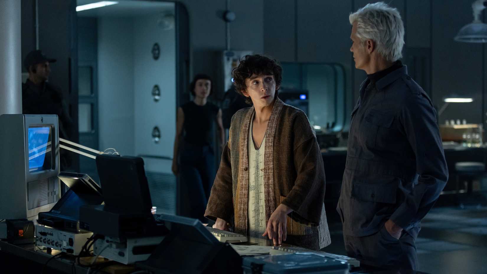 Boy Kavalier speaks with synthetic scientist Kirsh as Wendy, a Hybrid, approaches them from a distance.