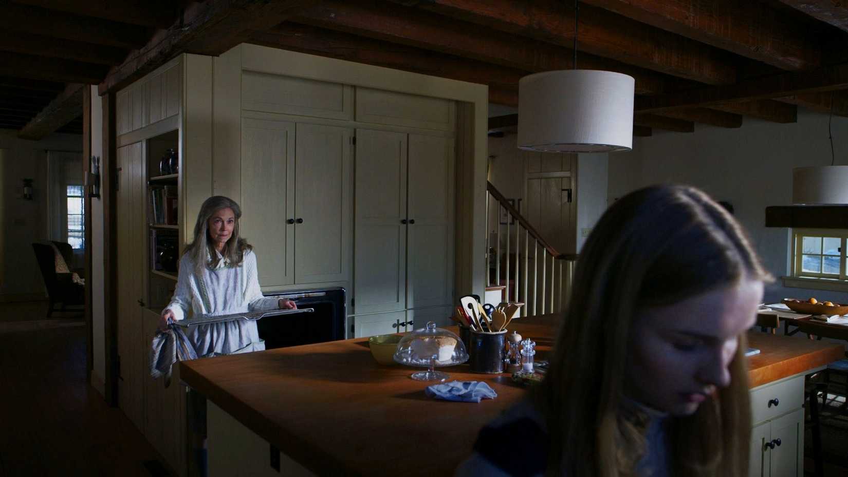 Becca (Olivia DeJonge) se encuentra en el primer plano de una cocina donde su Nana (Deanna Dunagan) le pide que limpie el horno en una escena de la visita.