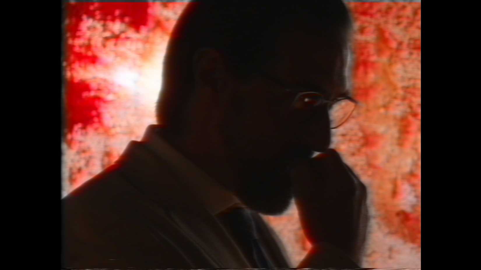 In a blurry close-up, a man resting his hand against his mouth pensively is silhouetted against a window covered with blood and slime in the V/H/S Halloween segment "Diet Phantasma"