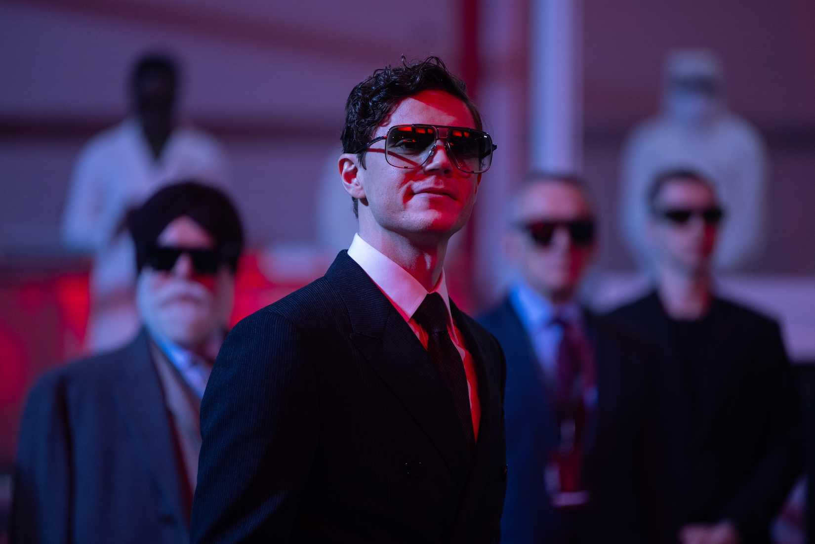 Evan Peters em Tron: Ares, sorrindo mal -intencionado em um terno e óculos escuros