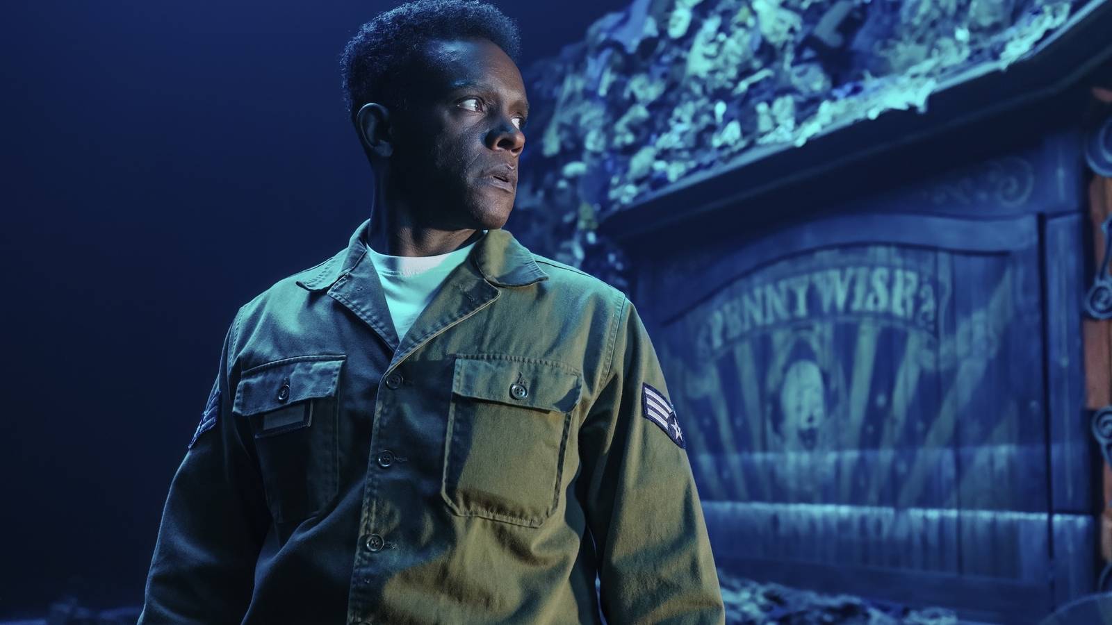 Chris Chalk as Dick Hallorann standing behind a Pennywise attraction in IT: Welcome to Derry
