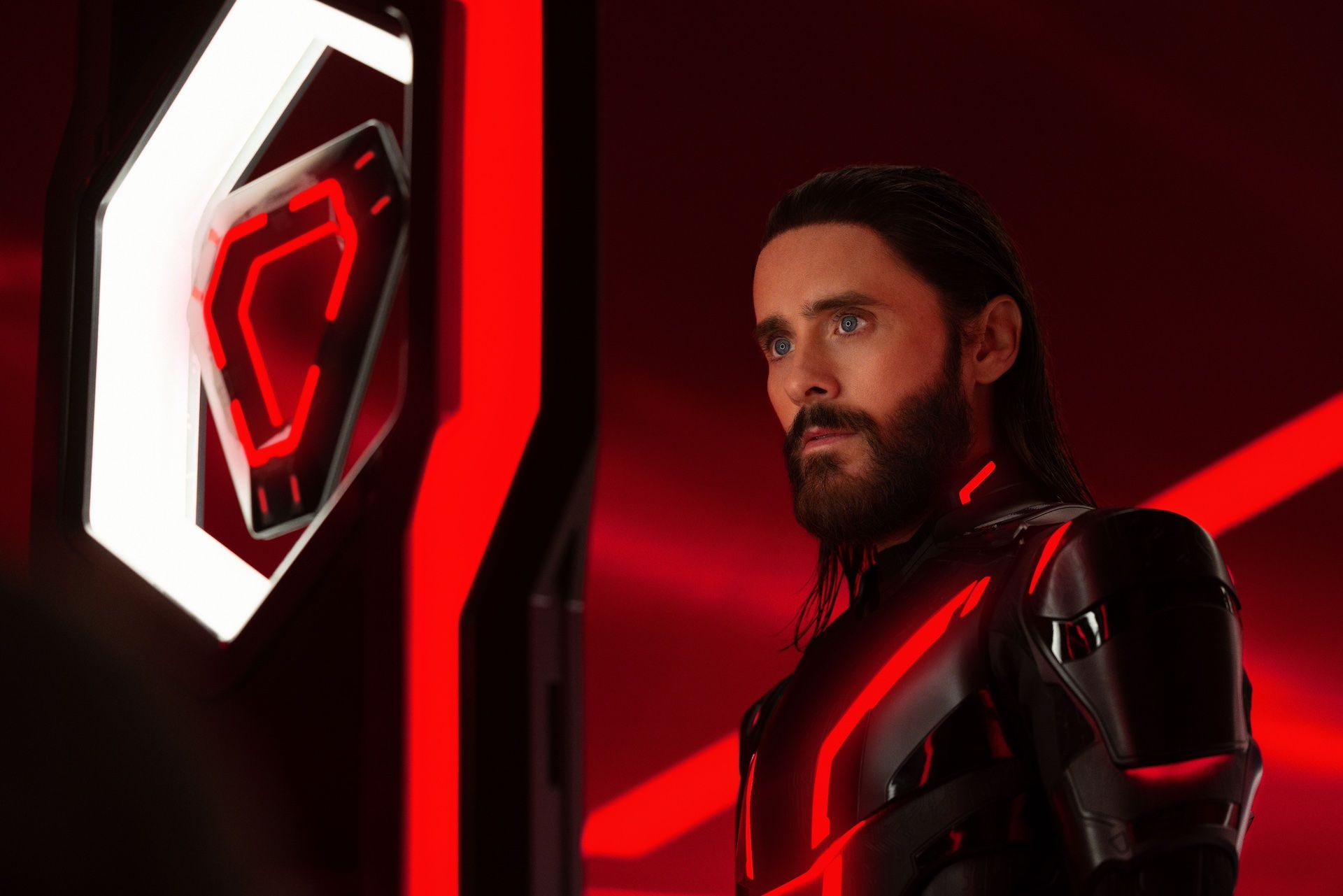 Ares (Jared Leto, in a black body suit) stands in a red-lit neon space in Tron: Ares