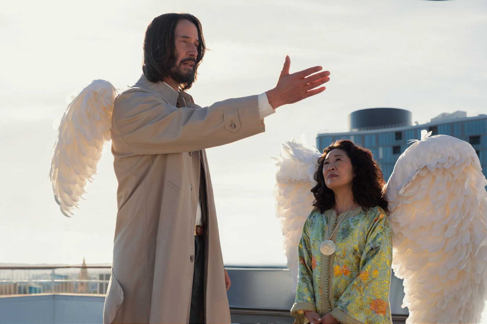Keanu Reeves as Gabriel with small wings reaches out while Sandra Oh’s angel looks on
