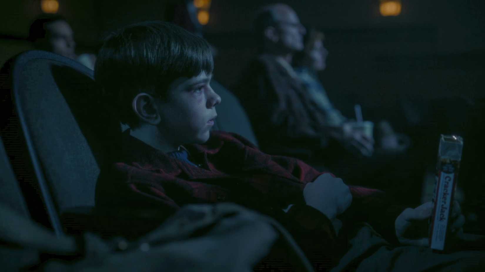 A young boy (Miles Ekhardtit) sitting in a dark theater from It: Welcome to Derry
