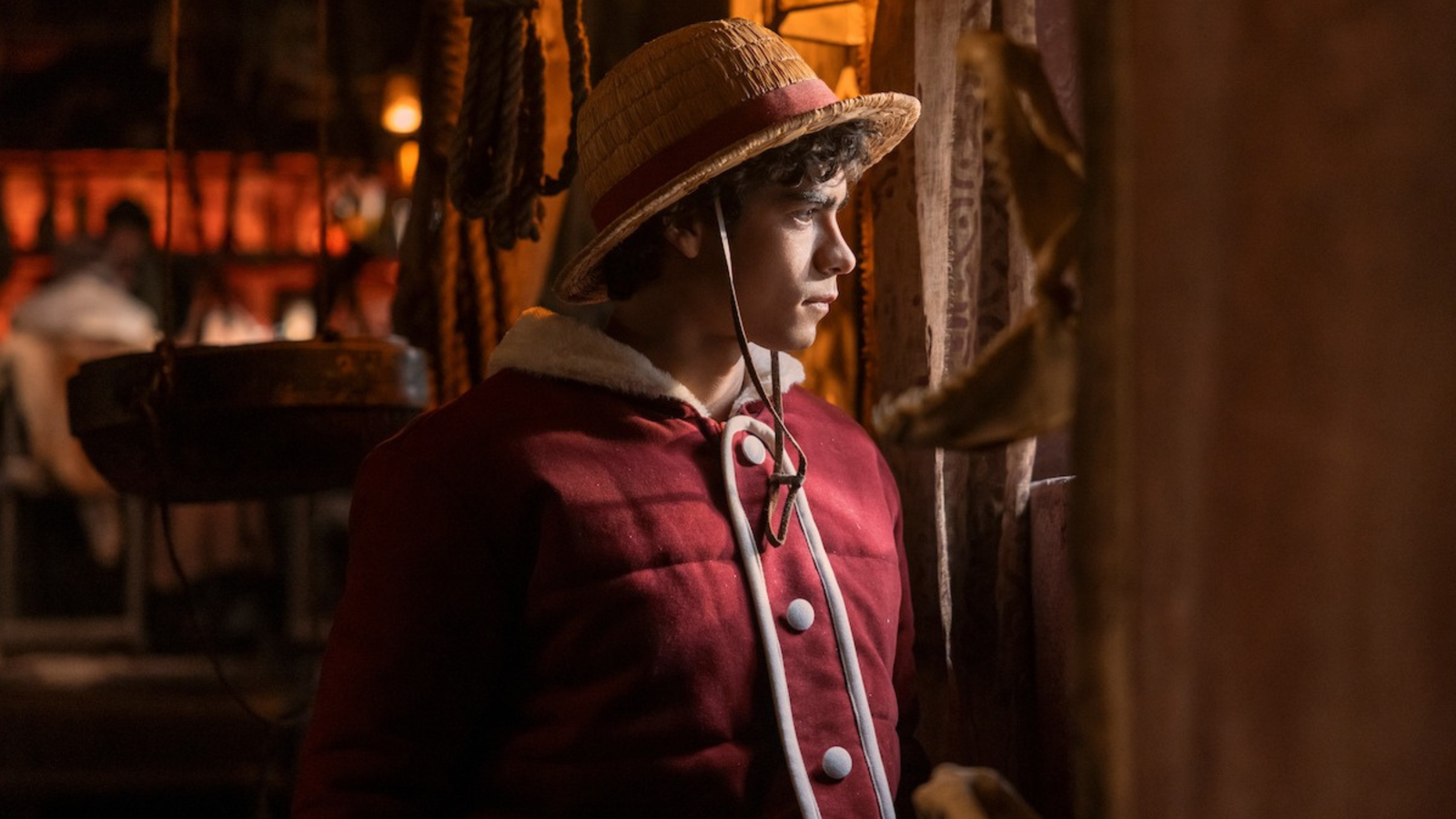 Iñaki Godoy as Luffy standing in a coat, gazing out from a ship's window in Netflix's live-action One Piece