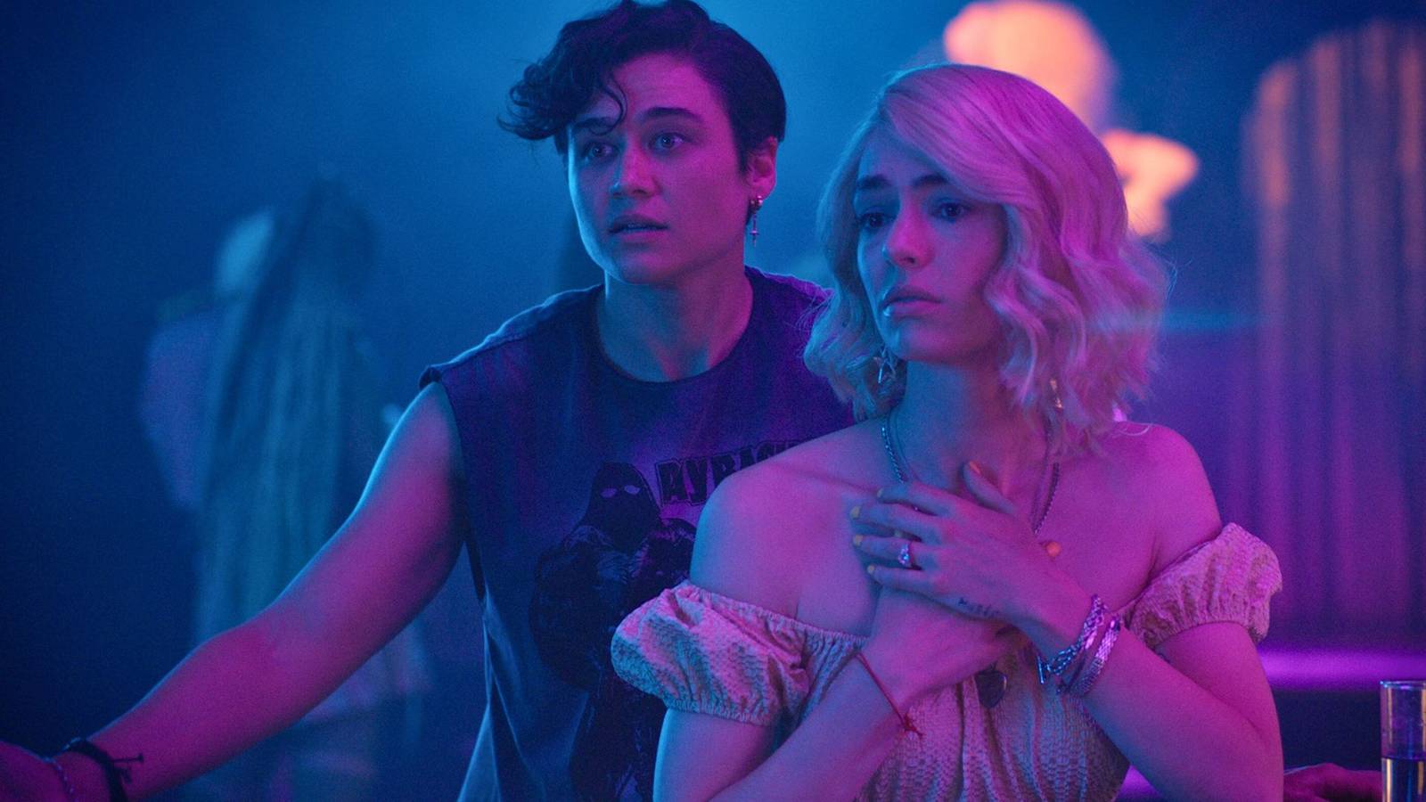 Dre (Katy O'Brian) and Kelsey (Jack Haven) in a neon club setting from Queens of the Dead