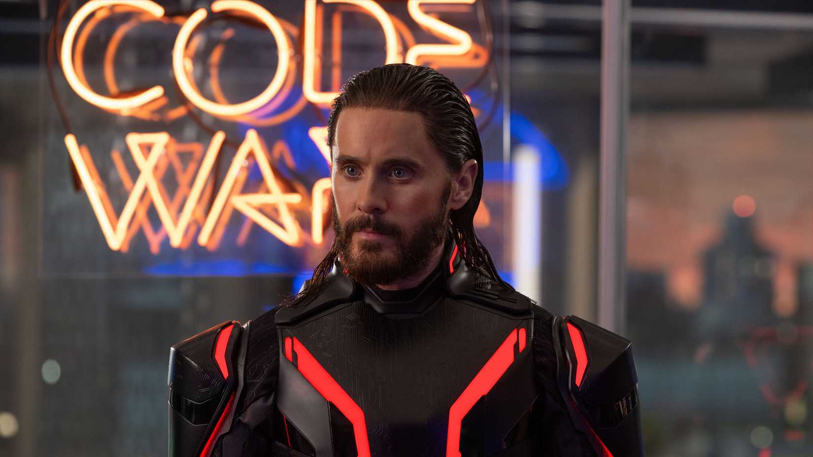 Jared Leto as Ares stands in front of a Code Wars sign in Tron: Ares