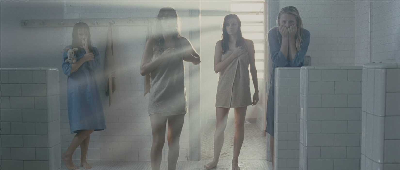 Four patients watch from a distance as Kristen has a breakdown in the shower in a scene from The Ward.