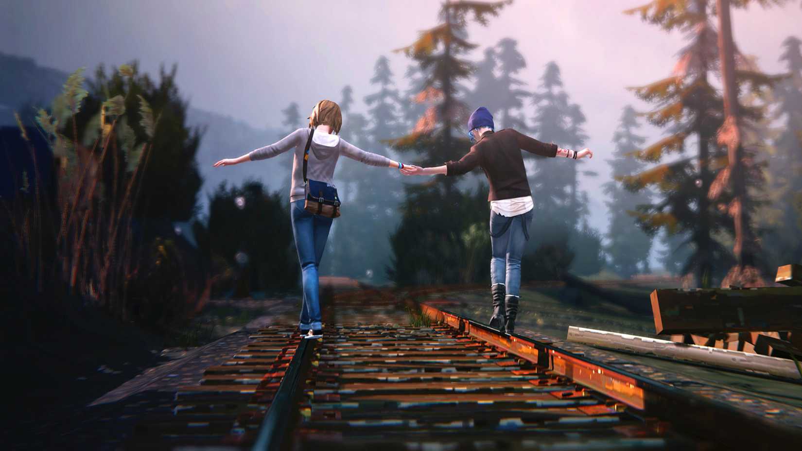 Chloe and Max hold hands as they balance on some train tracks.