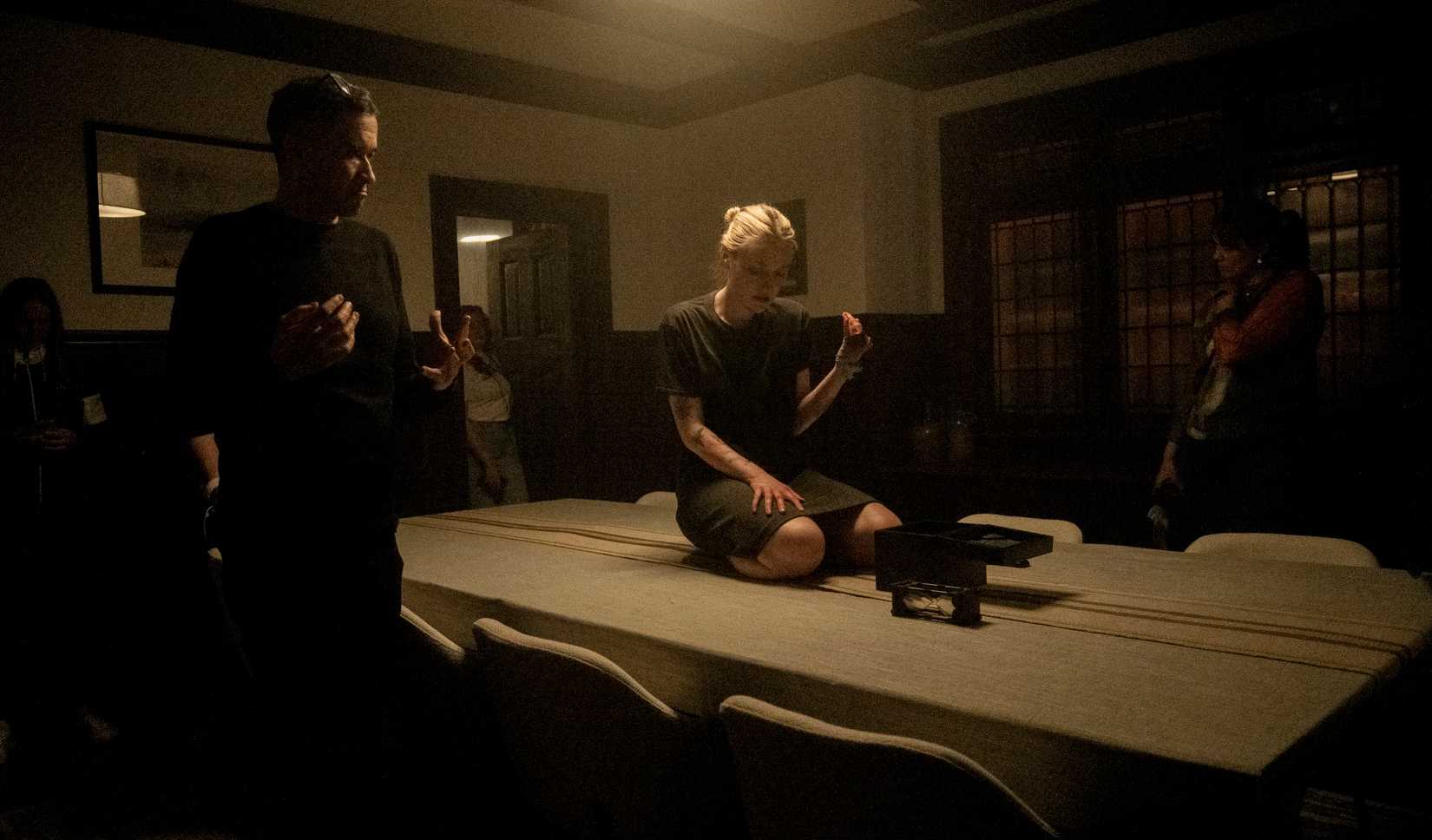 Director Bryan Bertino stands by with cameras as Dakota Fanning kneels on a kitchen table on the set of Vicious