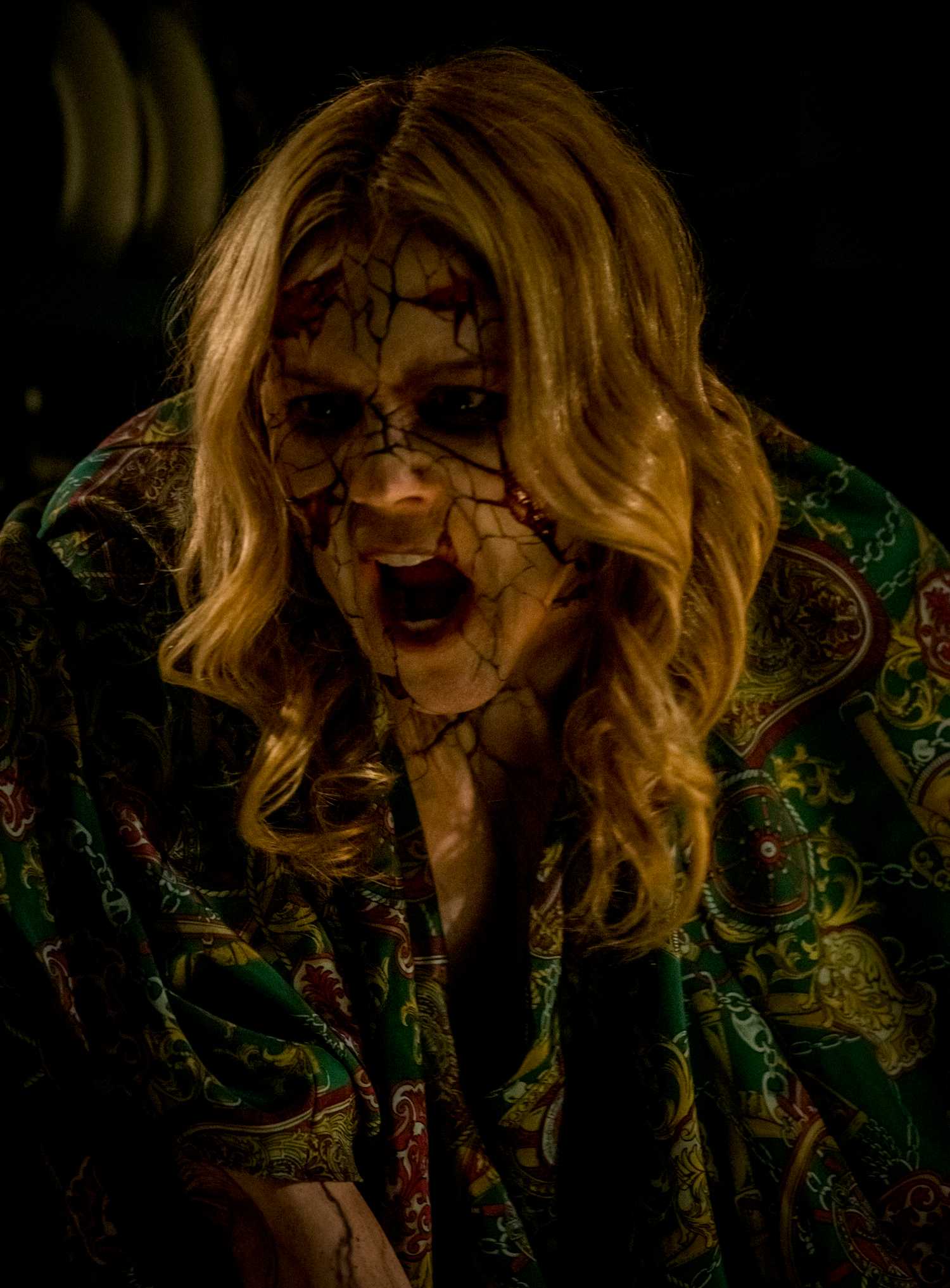 A woman in the dark, her face covered with thick, dark streaks of blood, screaming in Vicious