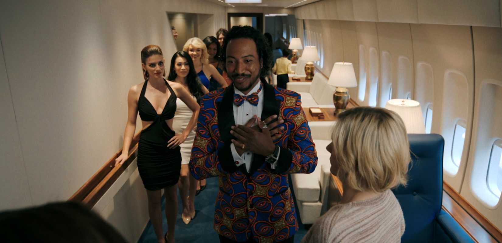 Koumba Diamanté (Samba Schutte) welcoming passengers on a lavish plane in Pluribus