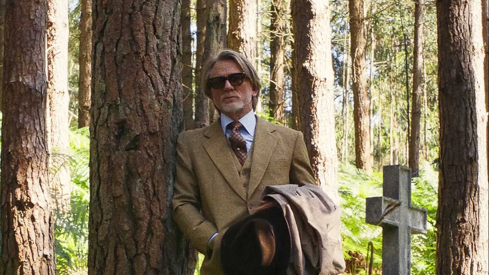 Benoit Blanc, played by Daniel Craig, lurks in the forest surrounding the church in a scene from Wake Up Dead Man: A Knives Out Mystery.
