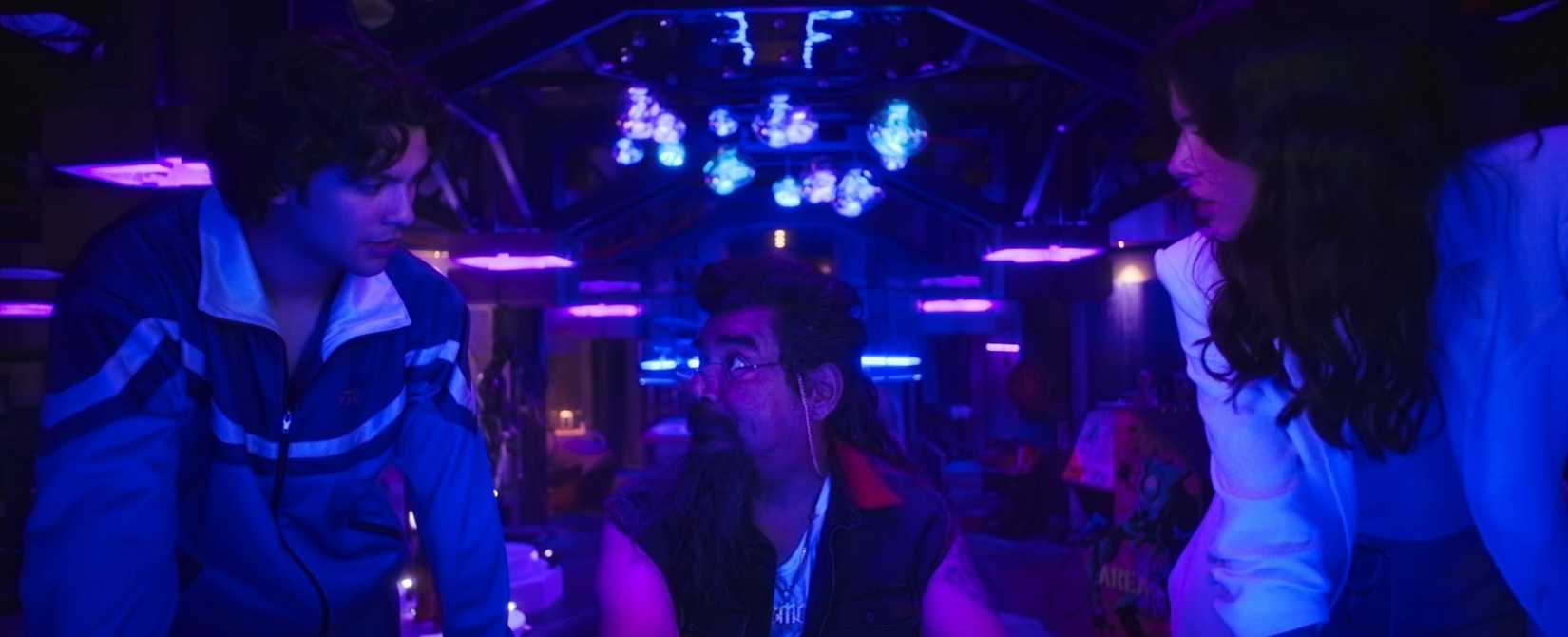 Jaime, su tío y su nueva amiga (¿o posible interés amoroso?), Jenny, se reúnen en una guarida similar a la Baticueva de Blue Beetle en una escena de la película de superhéroes de DC, Blue Beetle.