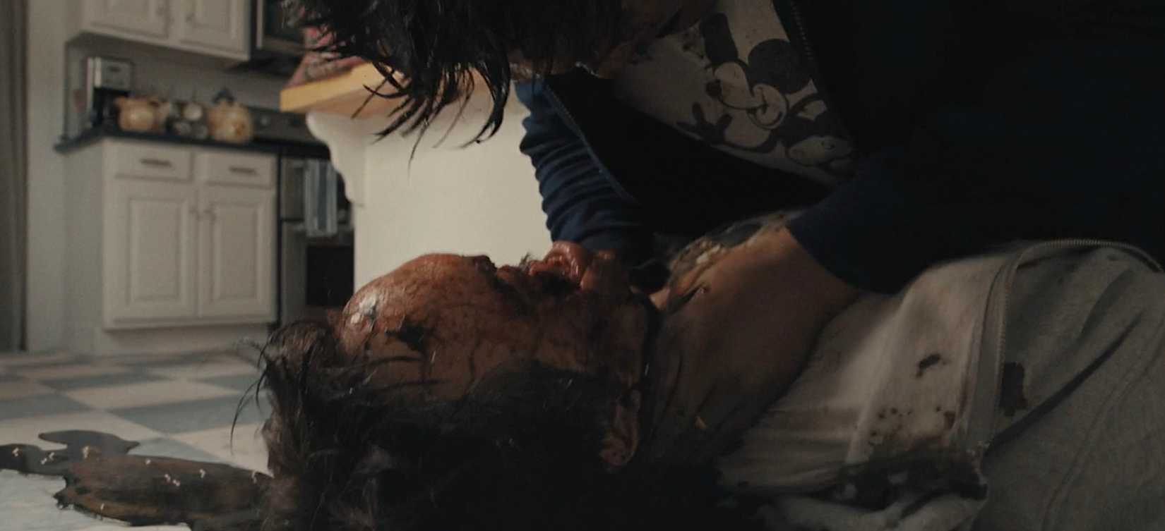 Marcus (Benedict Wong) pulls back from head-butting his husband Terry, whose face is caved-in and bloody, in Weapons