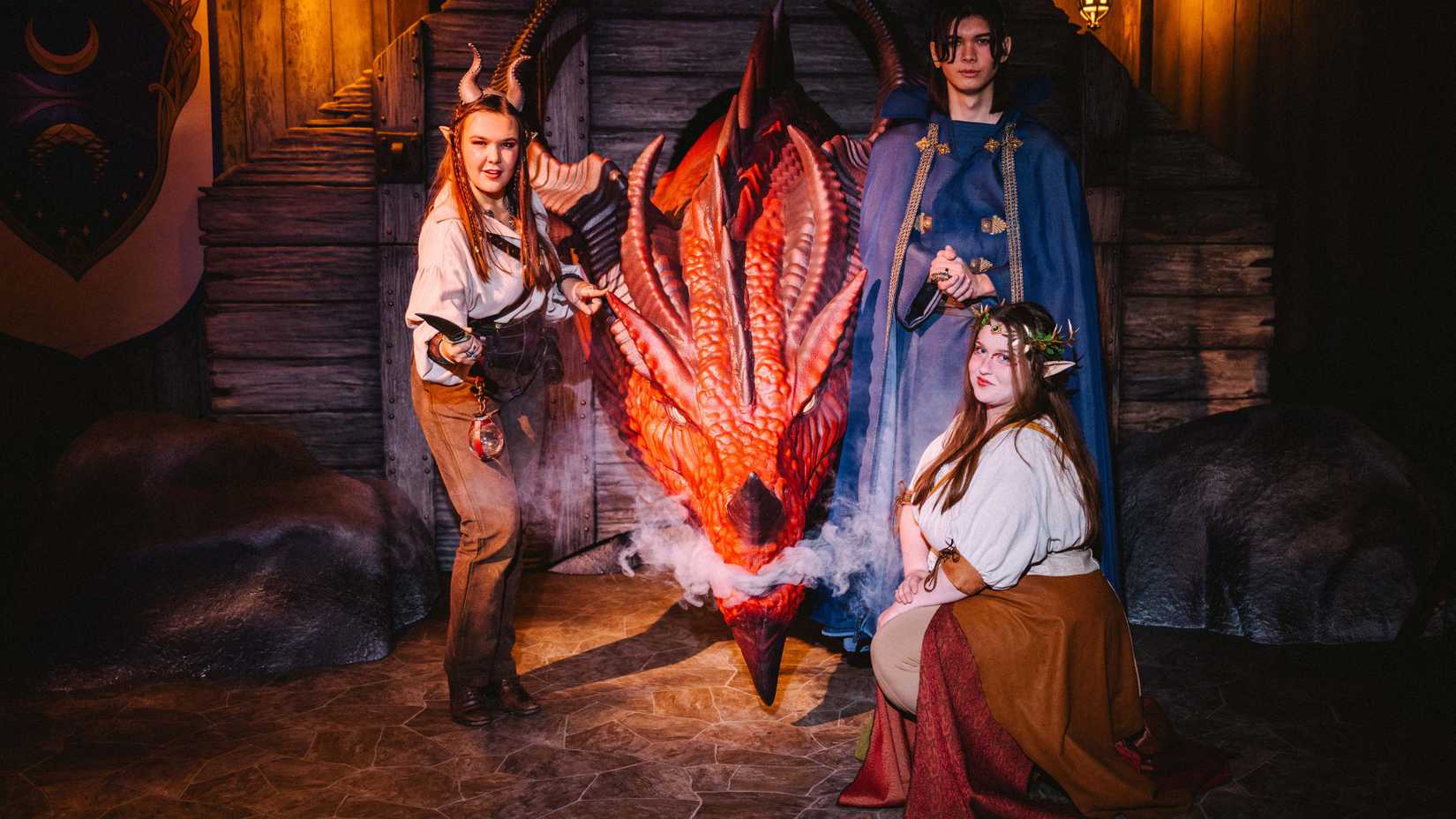 Cast members from Dungeons & Dragons: The Immersive Quest stand around the smoking head of the red dragon Ashardalon.