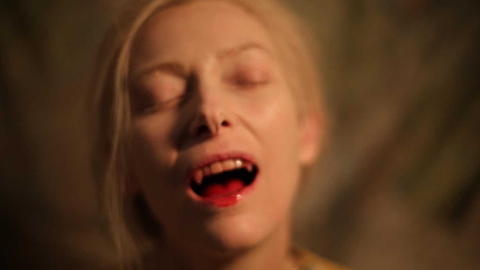 An out of focus shot of Tilda Swinton as Eve with a slightly bloody fanged mouth from Only Lovers Left Alive