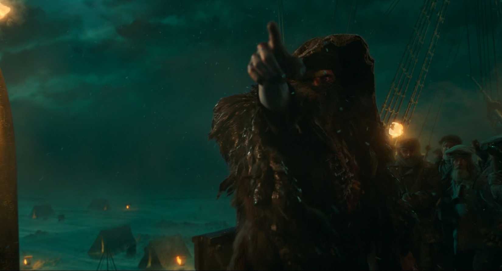 The Creature from Guillermo del Toro's Frankenstein, played by Jacob Elordi, points menacingly from within his tattered cloak