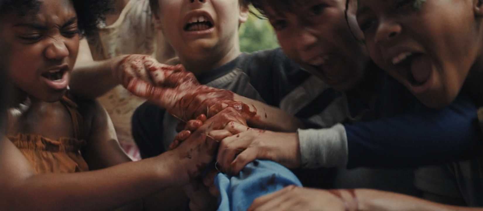A mob of blood-smeared children wrench at the twisted, bloody arm of an off-screen figure in Weapons