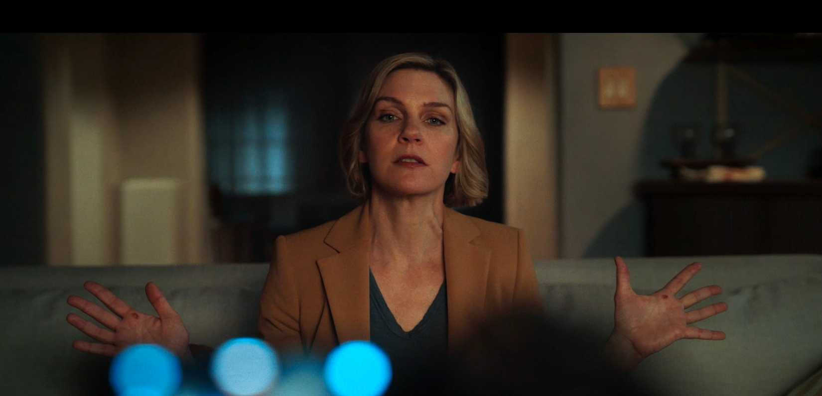 Carol (Rhea Seehorn) holds up her hands, palms up toward the camera, as she speaks into a camcorder in Pluribus