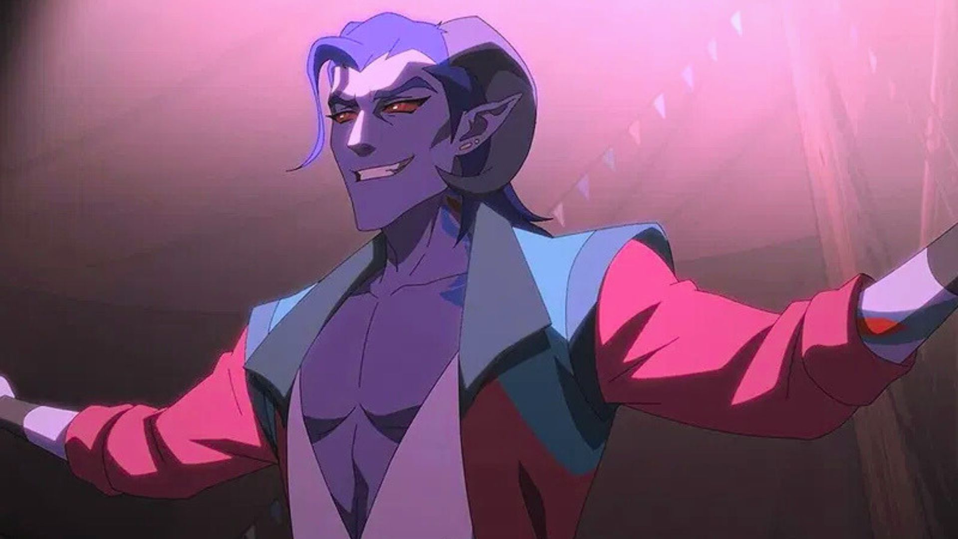 Mollymauk (Taliesin Jaffe) stands in a circus tent. He is a tiefling, with ram-like horns, and an open shirt that shows off his muscular chest. He is grinning under the spotlight.