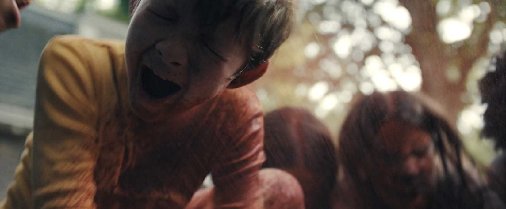 A blood-covered young boy screams in rage as he's sprayed with more blood in a scene from Zach Cregger's Weapons