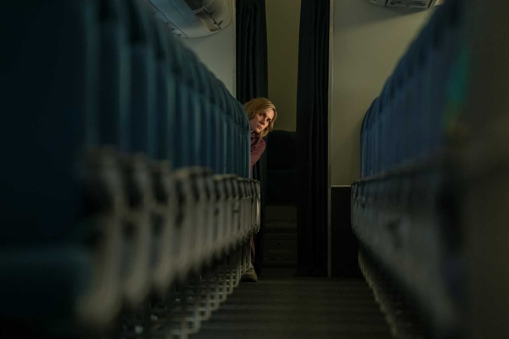 Carol (Rhea Seehorn) looking down the aisle of an empty jumbo jet in Pluribus