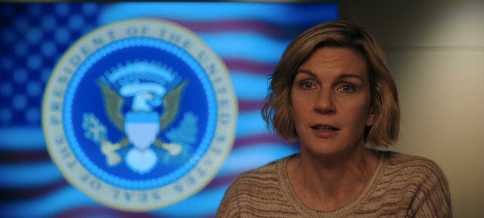 Carol (Rhea Seehorn) standing before the Presidential Seal in Pluribus