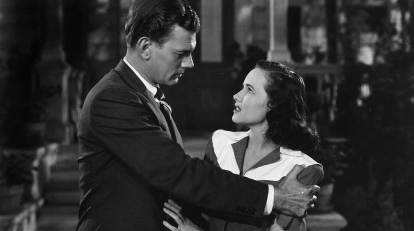 A grim-looking man grabs the arms of a worried young woman in Alfred Hitchcock's Shadow of a Doubt