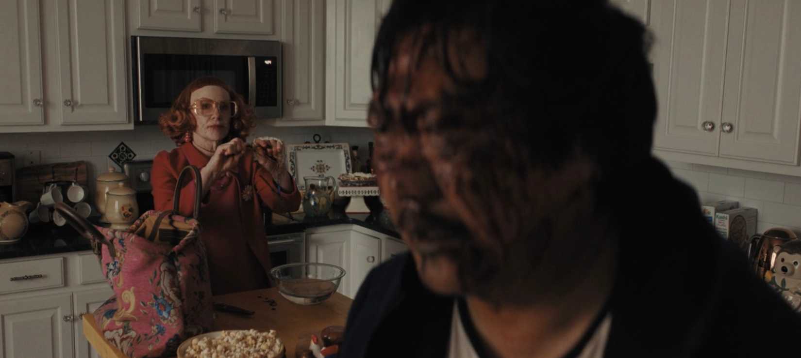 Gladys (Amy Madigan) holds up a thorny branch as Marcus (Benedict Wong) stands in the foreground, covered in blood and black bile, in a scene from Weapons