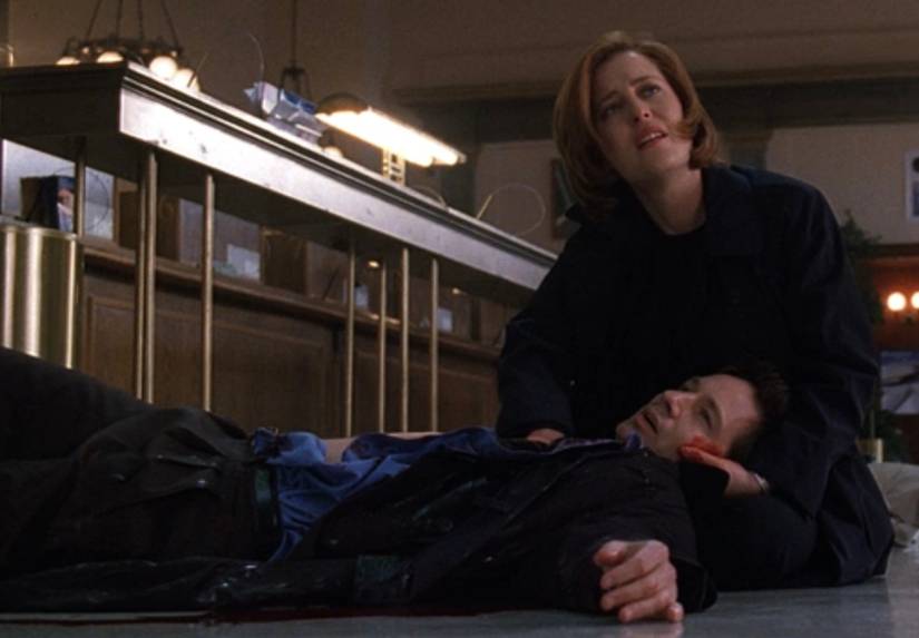 An episode of The X-Files in which Dana Scully (Gillian Anderson) sits on the floor of a bank holding a bleeding Fox Mulder (David Duchovny). "Monday"